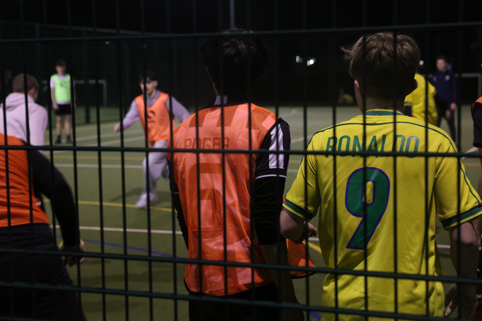 Players beside the five-a-side pitch under the floodlights